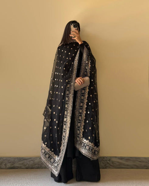 Front view of Black Floral Cotton Suit with Pure Fox Georgette kurta featuring potli button detailing, embroidered dupatta with sequin work, and a comfortable micro cotton palazzo.